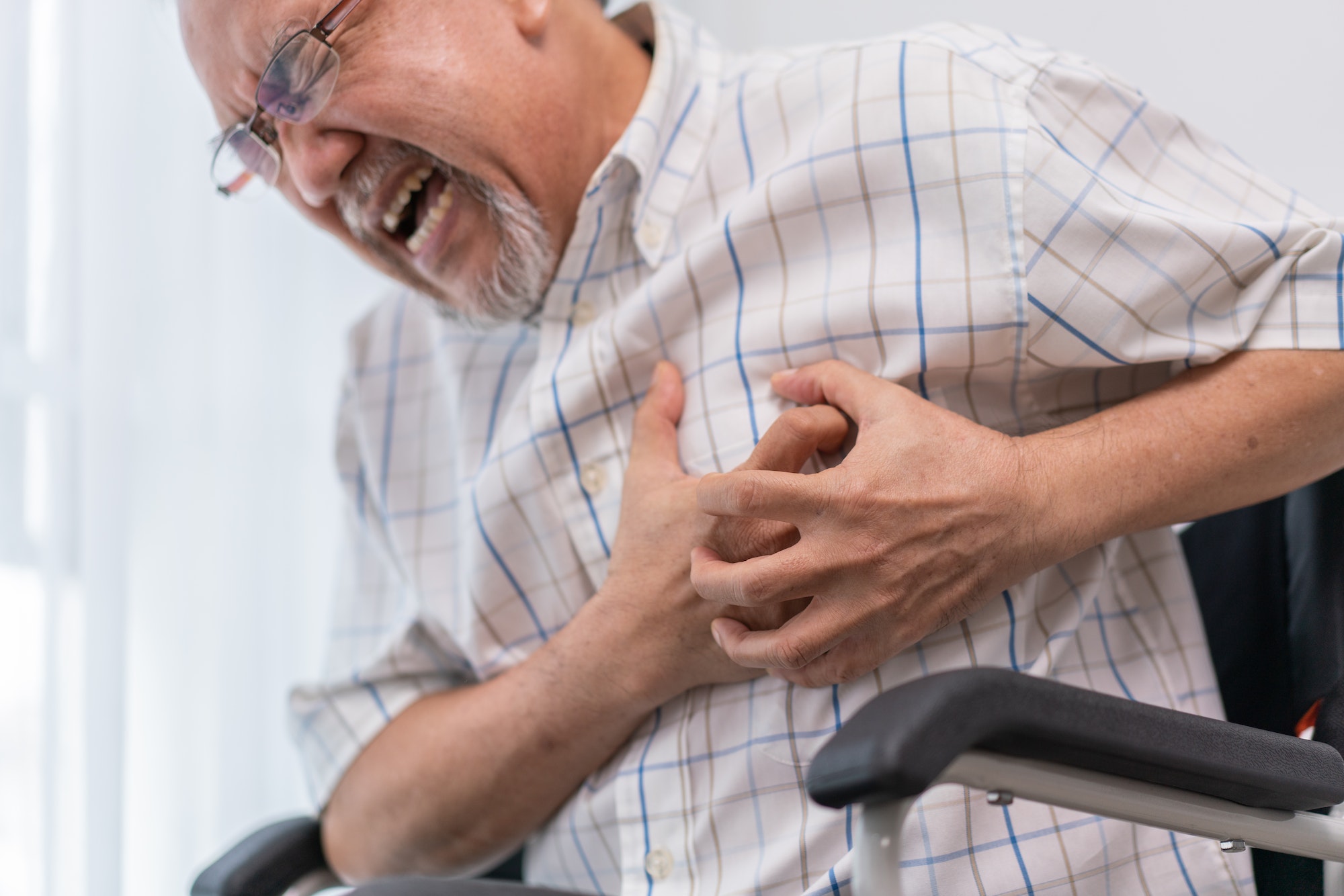 Asian senior man suffering from heart attack on wheelchair